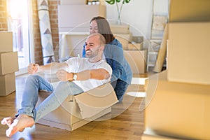 Funny and crazy couple having fun riding a cardboad box as a car, smiling happy and laughing at new home