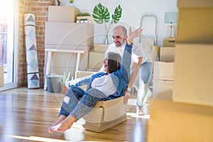 Funny and crazy couple having fun riding a cardboad box as a car, smiling happy and laughing at new home