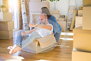 Funny and crazy couple having fun riding a cardboad box as a car, smiling happy and laughing at new home