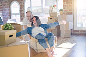 Funny and crazy couple having fun riding a cardboad box as a car, smiling happy and laughing at new home