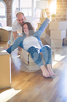 Funny and crazy couple having fun riding a cardboad box as a car, smiling happy and laughing at new home