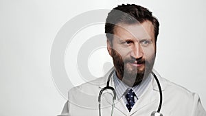 Funny crazy doctor grimaces and grumbles. Male doctor on white background looks at camera and grimaces, makes funny face