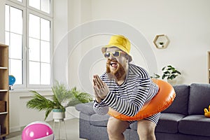 Funny crazy man with inflatable circle pretends to be swimming at home in living room.