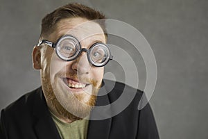 Closeup portrait of a funny crazy nerd in round frame glasses smiling at the camera