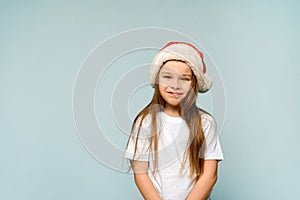 Funny cute baby girl in santa hat on blue background. Christmas and New Year concept