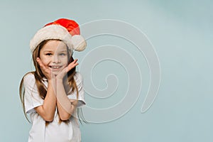 Funny cute baby girl in santa hat on blue background. Christmas and New Year concept