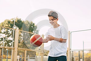 Funny cute boy athlete leads the ball in a game of basketball. A boy plays basketball after school. Sports, healthy