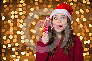 Funny cute girl in santa claus hat with christmas lollypops