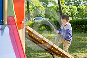 Funny cute happy baby playing on the playground. The emotion of happiness, fun, joy. Active little boy playing on playground