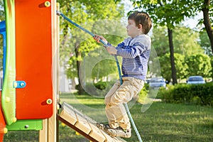 Funny cute happy baby playing on the playground. The emotion of happiness, fun, joy. Active little boy playing on playground