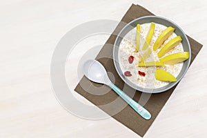 Funny cute kids childrens babys breakfast lunch oatmeal porridge in bowl look like hedgehog decoration with apple, dried cherry