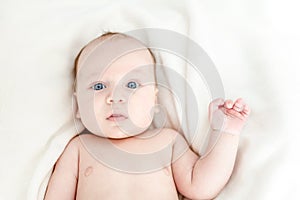 Funny cute little boy lying on a bed. Surprised and frightened emotion on child face. Waving a hand , hello world concept. Top vi