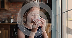 Funny cute little girl drinking glass of milk or yoghurt.