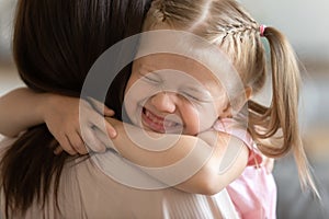 Funny cute little girl smiling embracing foster care parent mum