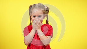 Funny cute little shy girl laughing closing mouth with hands. Portrait of beautiful blond Caucasian child with grey eyes
