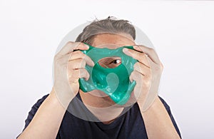 Funny dad holding a green slime in front of his face and looking through its hole