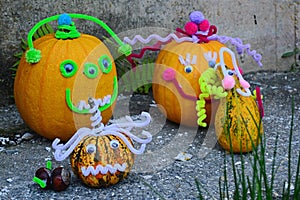 Funny decorated pumpkin heads as autumn decoration on stone slab in front of the house wall
