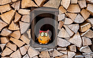 Funny decoration owl standing in the middle of a wood stack