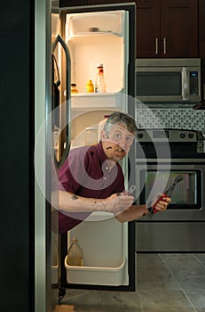 Funny dirty appliance repair homeowner man in refrigerator photo