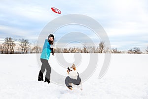 Funny dog walk in the snow, woman playing frisbee with her dog, winter season