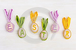 Funny Easter concept. letters Easter and wooden eggs with fabric ears as bunny