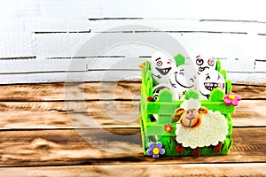 Funny easter eggs with different funny faces in the basket on white and wooden.