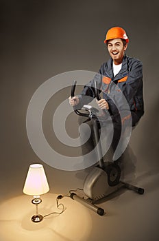 Funny electrician sitting on exercise bike generate electricity photo