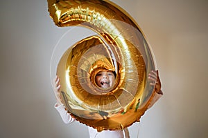 Funny emotional child girl with golden balloon.