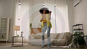 Funny energetic young African American ethnic girl happy smiling woman dancer dancing at home living room active