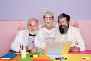 Funny excited business group of young and old confident business people using computer while spending time in the office