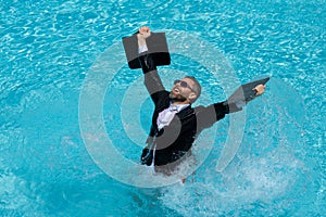 Funny excited businessman in suit with laptop in swimming pool. Crazy business man on summer vacation. Amazed