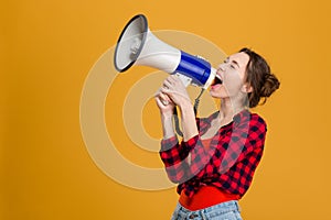 Funny excited young woman shouting in megaphone