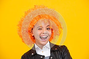 Funny face. Beautiful teenage girl in wig isolated on yellow. Funny clown wig.