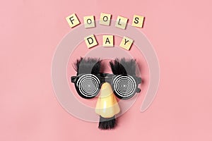 funny face - fake eyeglasses, nose and mustache, confetti, sequins on pink background Happy fools day concept 1st April party