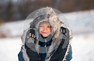 Funny face of little boy on snow winter nature. Funny kid in winter clothes. Children play outdoors in snow. Kids