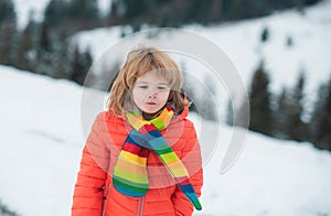 Funny face of little boy on snow winter nature. Funny kid in winter clothes. Children play outdoors in snow. Kids