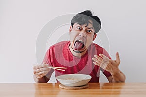 Funny face of man eat very hot and spicy instant noodle.