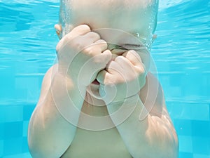 Funny face portrait of baby boy swimming and diving underwater