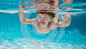 Funny face portrait of child boy swimming and diving underwater with fun in pool.