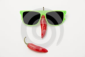 Funny face with a smile of sunglasses and hot chili peppers on a