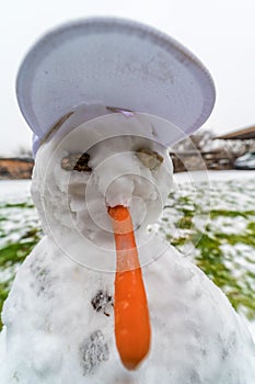 Funny face of a snowman with a long carrot as a nose
