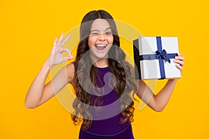 Funny face. Teenager kid with present box. Teen girl giving birthday gift. Present, greeting and gifting concept.