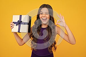 Funny face. Teenager kid with present box. Teen girl giving birthday gift. Present, greeting and gifting concept.