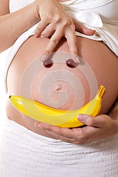 Funny faces of the fruit on the abdomen of a pregnant woman