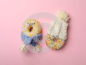 Funny faces made with donuts and warm clothes on background