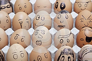 Funny faces on painted on brown eggs arranged in carton