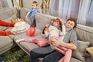 Funny family celebrating birthday with cake at home