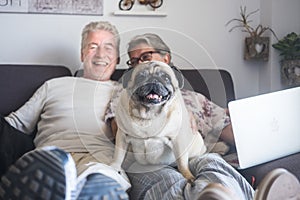 Funny family concept with couple of cheerful caucasian people senior man and woman sit down on the sofa with laptop computer and