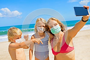 Funny family in face masks taking selfie photo on beach