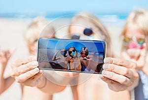 Funny family in face masks taking selfie photo on beach